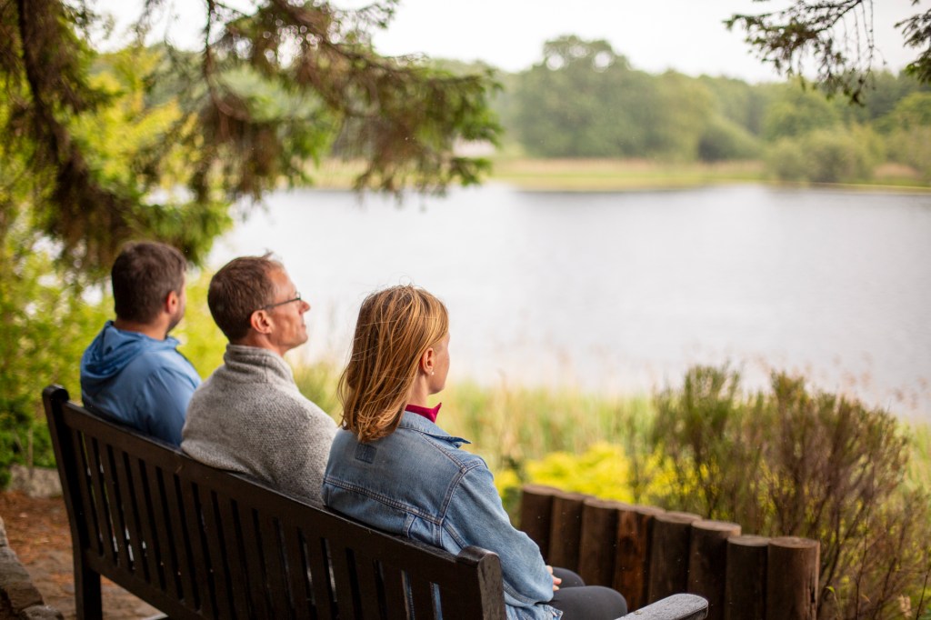 Sitting calmly on a bench looking out over a beautiful lake.
